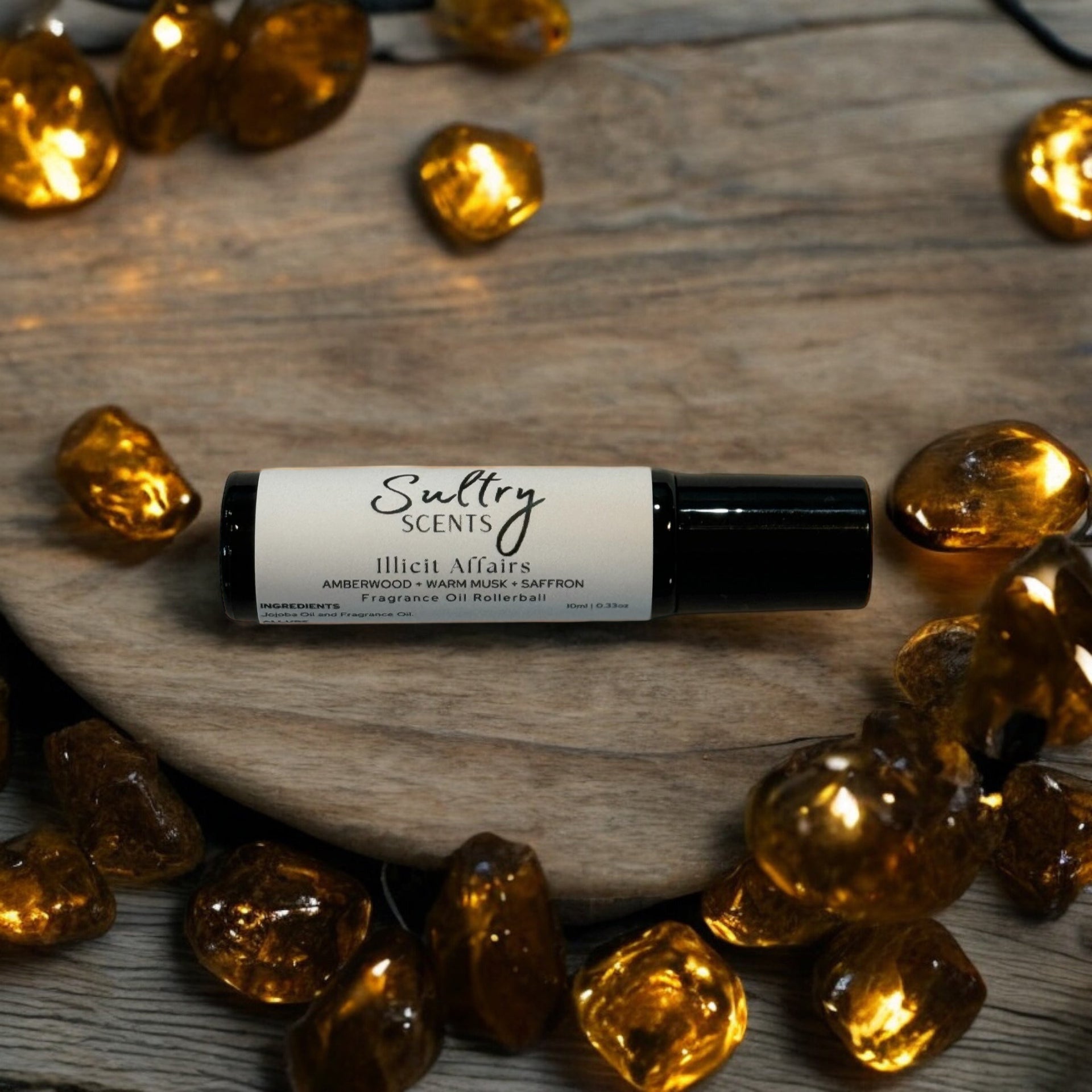 Roll-on perfume oil in a stylish glass bottle surrounded by decorative amber stones