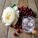 Black Cherry silk soap bar inspired image with fresh cherries, white flower, and a glass of ice water on wooden surface
