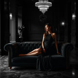 Elegant woman in black dress sitting on dark velvet sofa in luxurious room Black Saffron dupe roll on perfume