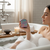 Woman in a luxurious bath holding Butterfly pea flower soap with bubbles and candles in the background