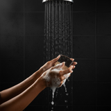 Person using fresh scented luxury handmade soap under a shower with rich lather