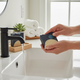 Glossier You inspired soap bar held over a modern sink with soft towels in the background