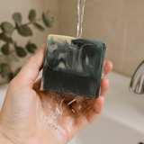Mens soap inspired by YSL Myslf with black and white marbled design being held under running water