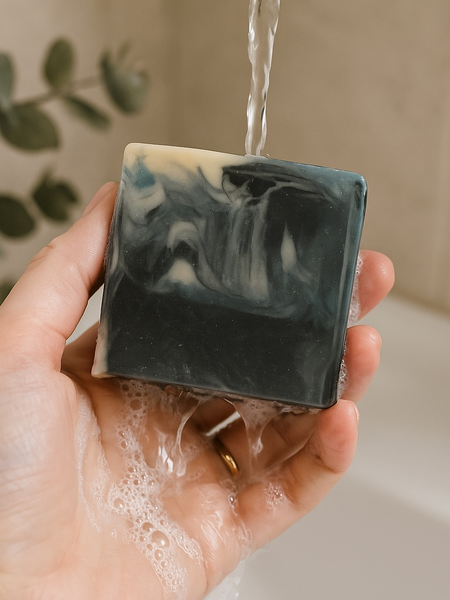 Mens soap inspired by YSL Myslf with black and white marbled design being held under running water