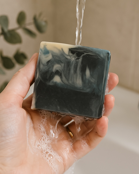 Mens soap inspired by YSL Myslf with black and white marbled design being held under running water