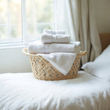 Odor Eliminating Clean cotton Room Spray by Sultry Scents with fresh white towels in woven basket on bed