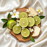 Phlur Missing Person inspired body spray ingredients featuring fresh bergamot slices, white flowers, and creamy wood on satin
