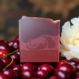 Black Cherry Silk soap bar by Sultry Scents with layered cherry red design surrounded by fresh cherries and white flower