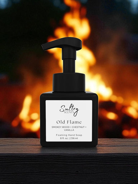 By the Fire inspired luxury foaming hand soap Sultry Scents Old Flame black square pump bottle on wood with campfire flames