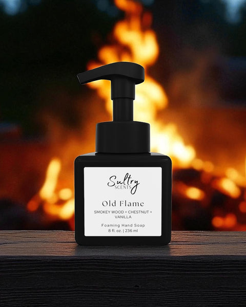 By the Fire inspired luxury foaming hand soap Sultry Scents Old Flame black square pump bottle on wood with campfire flames