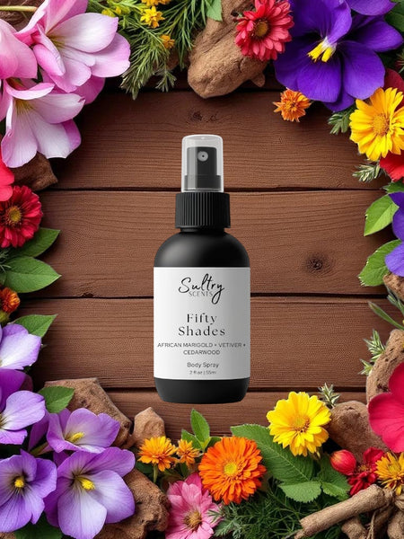 Sultry Scents black body spray bottle on wood backdrop surrounded by colorful flowers Byredo Inspired Bal D'Afrique Body Spray