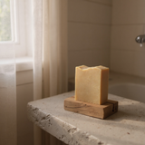 Handcrafted turmeric soap made with tallow displayed on a wooden soap dish in a bathroom setting