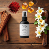 Black body spray bottle on wood with jasmine, amber resin and saffron highlighting Illicit Affairs fragrance by Sultry Scents.