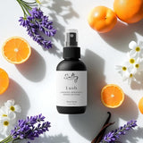 Sultry Scents Lush body spray surrounded by lavender, orange slices, and white flowers Libre perfume dupe Body spray