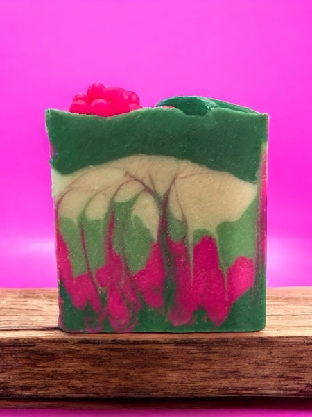 Pear Jam inspired handcrafted soap by Sultry Scents with green, cream, and pink swirls on wooden stand