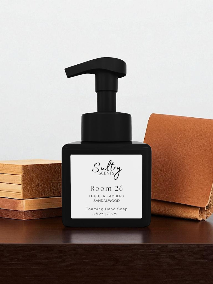 Room 26 foaming hand soap inspired by Santal 26 in a sleek black pump bottle on a wooden surface