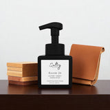 Room 26 foaming hand soap inspired by Santal 26 in a sleek black pump bottle on a wooden surface