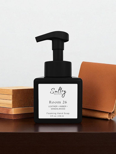 Room 26 foaming hand soap inspired by Santal 26 in a sleek black pump bottle on a wooden surface