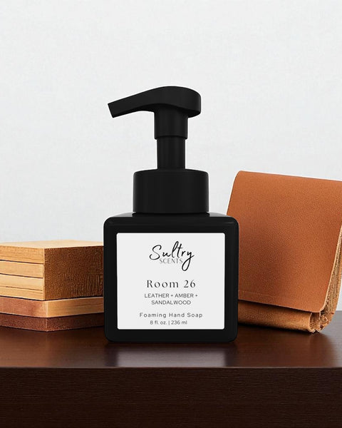 Room 26 foaming hand soap inspired by Santal 26 in a sleek black pump bottle on a wooden surface