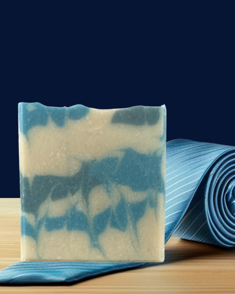 Sultry Scents artisanal marbled bar on wooden board next to blue tie Soap inspired by Polo Sport with grit.