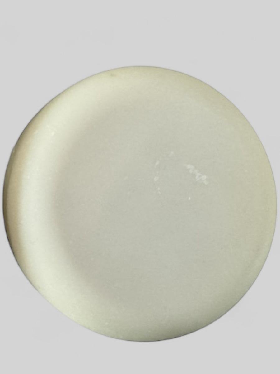 Round white solid dish soap bar from Sultry Scents on a gray background