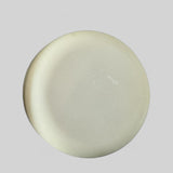 Round white solid dish soap bar from Sultry Scents on a gray background