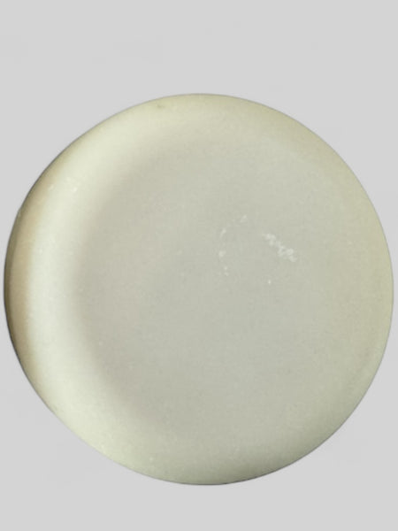 Round white solid dish soap bar from Sultry Scents on a gray background