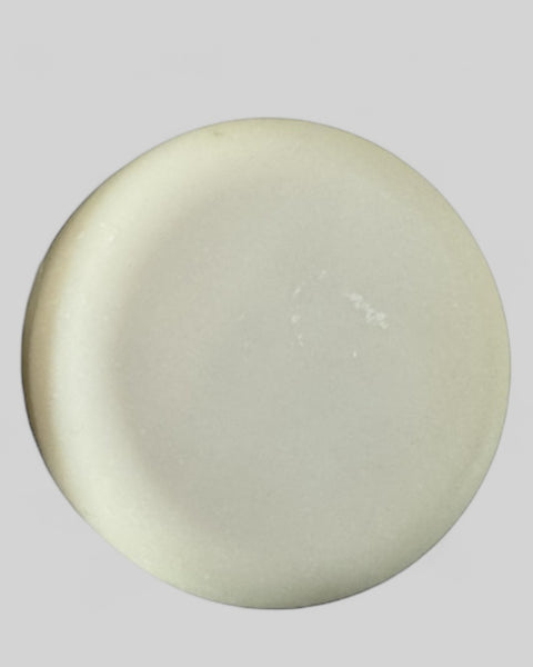 Round white solid dish soap bar from Sultry Scents on a gray background