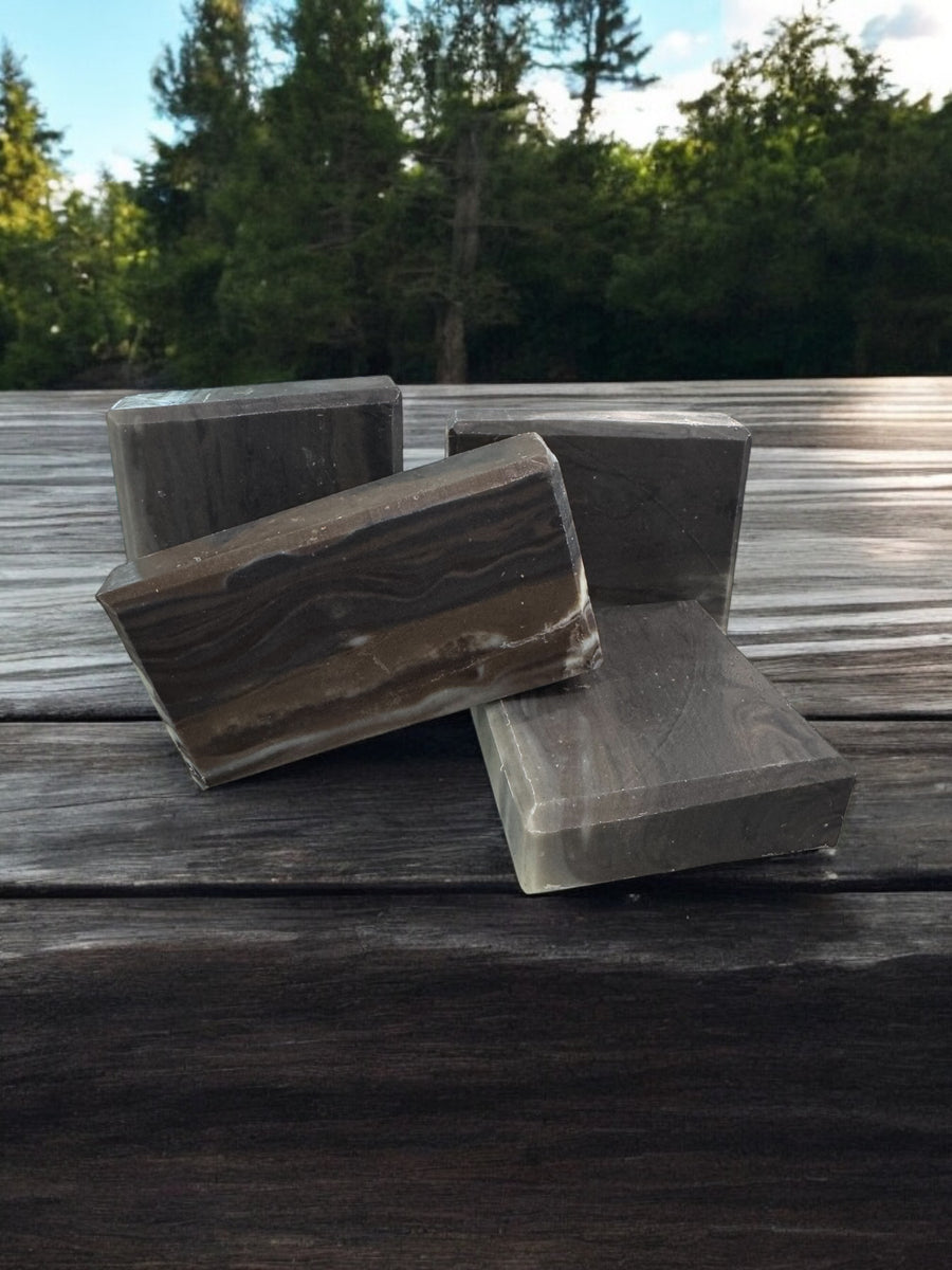 Natural wood fragrance soap bars arranged on a wooden surface surrounded by greenery