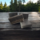 Natural wood fragrance soap bars arranged on a wooden surface surrounded by greenery