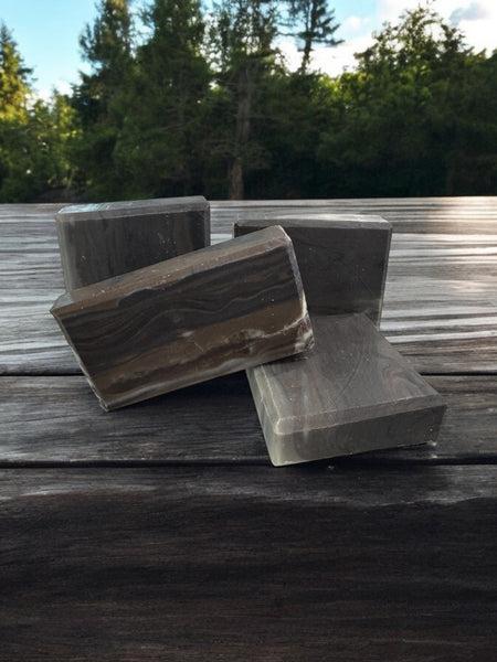 Natural wood fragrance soap bars arranged on a wooden surface surrounded by greenery