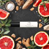 Sultry Scents wood sage and sea salt inspired roll on fragrance bottle surrounded by grapefruit slices and sea salt