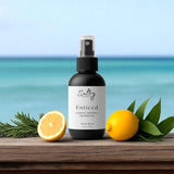 Sultry Scents Enticed odor eliminating luxury room spray bottle with lemons herbs on ocean backdrop