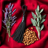 Tom Ford Fucking Fabulous dupe ingredients with lavender, almond nuts, sage leaves, and black tassel on red fabric